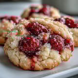 Freshly baked Soft Chewy Raspberry Sugar Cookies cooling on a wire rack, fluffy centers, vibrant raspberry specks, beside a bowl of extra berries.