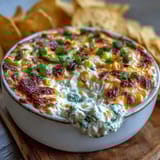 A warm scoop of Crack Corn Dip reveals creamy corn and green onions, a perfect appetizer for game day gatherings.