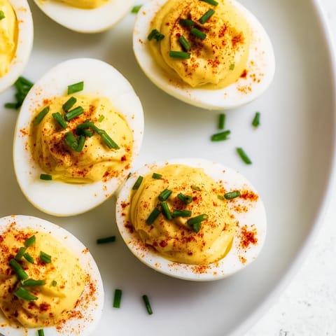 Halved deviled eggs with a tangy, mustard-spiked filling, perfect for party appetizers.