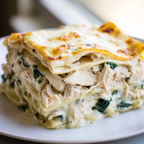 A rich slice of Chicken Alfredo Lasagna reveals creamy ricotta, spinach, and tender chicken layers.