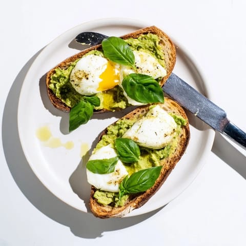 Warm Avocado Mozzarella Tartine garnished with fresh basil and a drizzle of olive oil.  