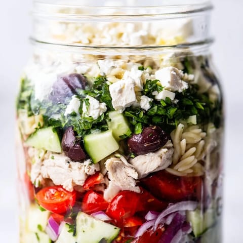Hearty Greek Pasta Chicken Salad Jars with creamy feta, crisp cucumbers, and tangy red wine vinaigrette for meal prep.