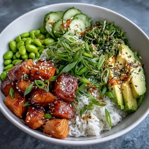 A colorful salmon rice bowl with tender baked salmon cubes, jasmine rice, avocado, cucumber, and a spicy sriracha mayo drizzle.  