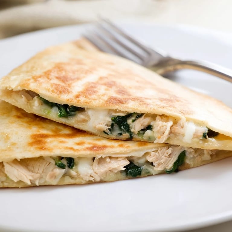 A rustic serving suggestion for Chicken and Spinach Quesadilla, sliced into triangles and garnished with fresh herbs, ready for a satisfying meal.