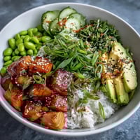 A colorful salmon rice bowl with tender baked salmon cubes, jasmine rice, avocado, cucumber, and a spicy sriracha mayo drizzle.  