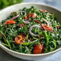 Vibrant dandelion greens salad with lemon vinaigrette, Parmesan shavings, and toasted pine nuts for a zesty, fresh Mediterranean side.
